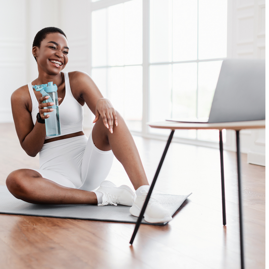 black woman with exercise clothing on drinking water practicing self-care
